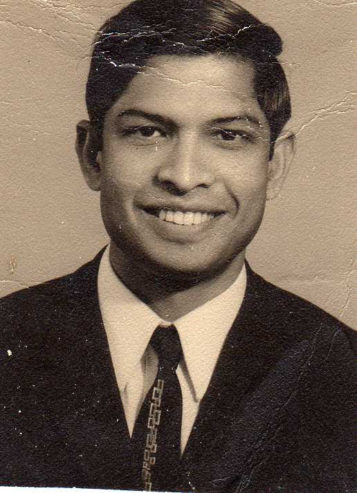 Studio portrait of a young man in a suit, smiling warmly at the camera.