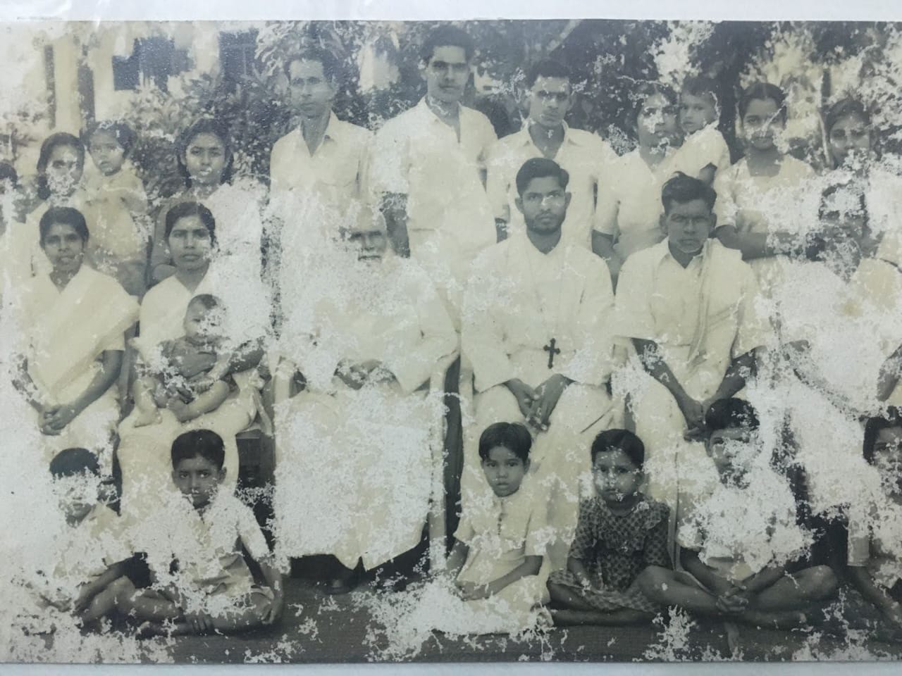 Old family group photograph with adults and children, showing significant wear and fading.